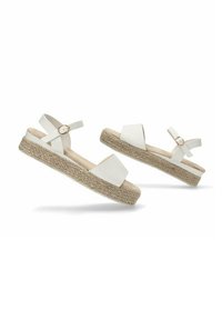 Sandalias espadrilles blancas con suela de yute trenzado, que presentan un diseño de tiras cruzadas y una correa ajustable en el tobillo. Textura suave y mate.