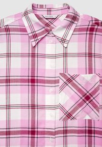 Pink and white plaid button-up shirt with collar and front chest pocket, featuring shades of red and dark lines in the check pattern.