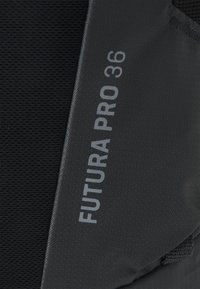 Rucsac din țesătură neagră cu text gravat "FUTURA PRO 36". Textură netedă, material durabil și un design structurat. Prezintă accente gri.