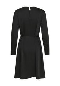 Robe noire à manches longues, avec un dos en forme de trou de serrure, une taille cintrée et une jupe évasée. Tissu lisse et uni avec des poignets à boutons.