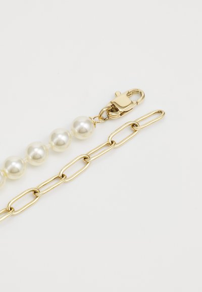 Bracelet en chaîne dorée avec des sections alternées de grandes perles blanches et d'une chaîne à maillons, doté d'une fermeture à cliquet. Texture lisse.