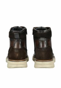 Botas marrones hasta el tobillo que combinan materiales de cuero suave y ante, con un diseño de caña alta, cierre de cremallera y suelas de goma blanca.