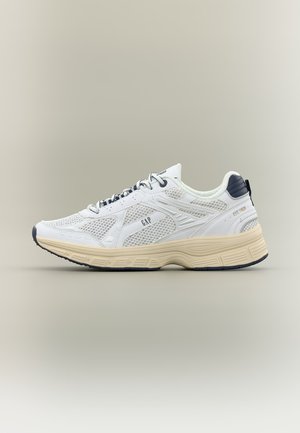 Weißer und beiger sportlicher Sneaker mit Mesh-Einsätzen, GAP-Logo an der Seite, dunkler Sohle und gepolstertem Fersenbereich vor schlichter Hintergrund.