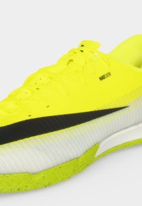 Φωτεινό κίτρινο παπούτσι για τρέξιμο Nike με μαύρο λογότυπο, λευκή ενδιάμεση σόλα και υφασμένη κίτρινη εξωτερική σόλα, με υλικό NIKESKIN στο πάνω μέρος.