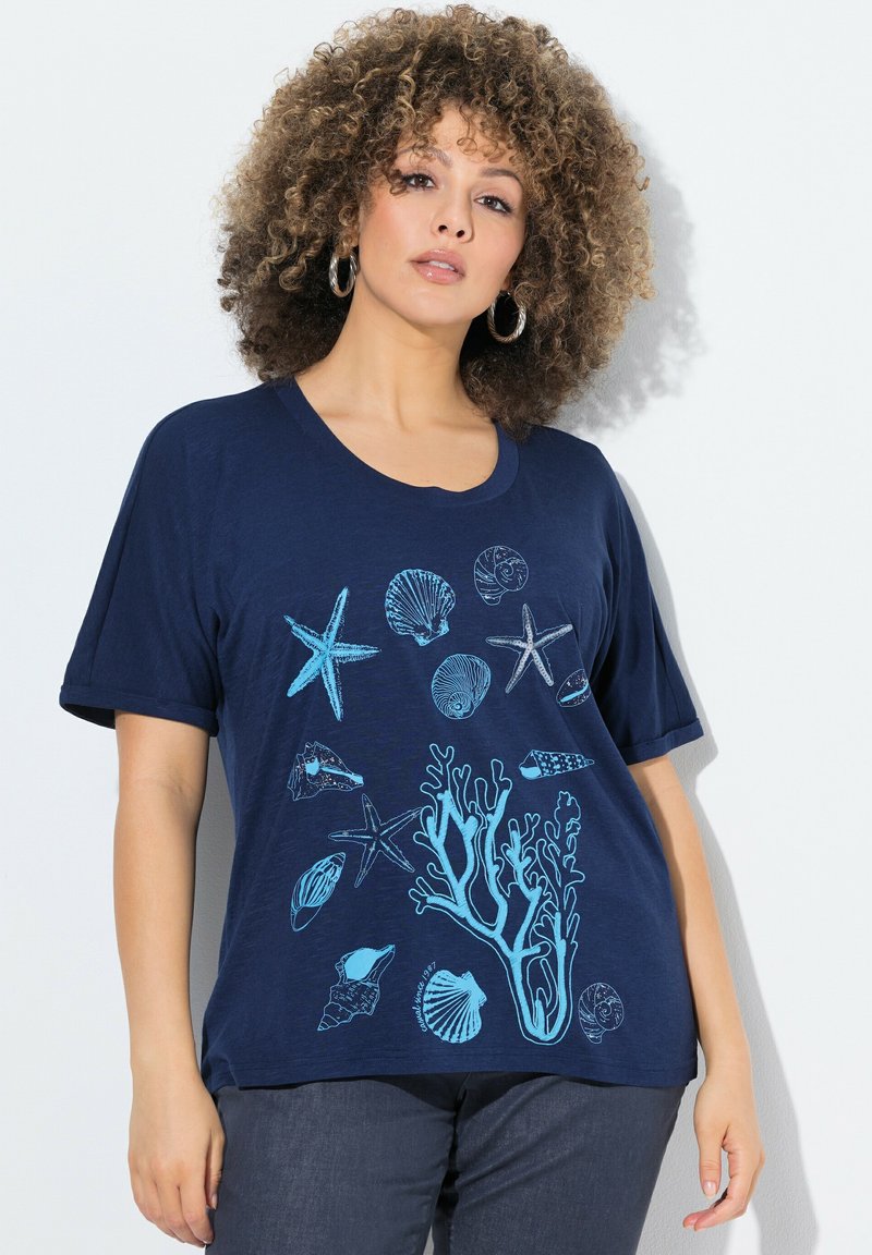 Námořnická modrá tričko vyrobené z měkké tkaniny, s světle modrými mořskými motivy včetně mušlí, hvězdic a korálů. Krátké rukávy.