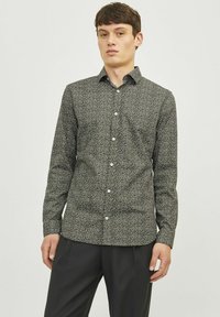 Chemise noire à boutons avec un petit motif floral blanc. Coupe slim, manches longues et design de col classique. Texture de tissu lisse.