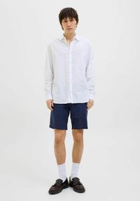 Witte button-up shirt, donkerblauwe shorts, witte sokken en donkere schoenen. Effen stof, comfortabele pasvorm, casual ontwerp, algehele lichte uitstraling.