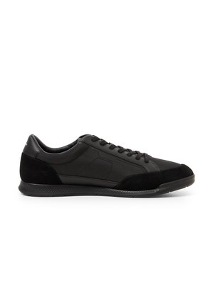 Schwarzer flacher Sneaker mit Obermaterial aus Leder und Stoff, Schnürverschluss und profilierter Gummisohle, seitliche Ansicht.