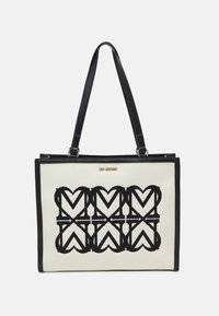 Svart och vit tote-väska med hjärt-mönster, tillverkad av kanvas med svarta läderdetaljer och remmar. Guld "LOVE MOSCHINO"-logotyp på framsidan.