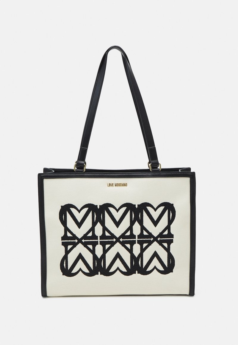 Svart och vit tote-väska med hjärt-mönster, tillverkad av kanvas med svarta läderdetaljer och remmar. Guld "LOVE MOSCHINO"-logotyp på framsidan.
