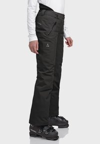 Schwarze Skihosen aus strapazierfähigem Material, mit schlanker Passform, Reißverschlusstaschen und einem Logo- akzent auf dem Oberschenkel. Verstärkte Bündchen.