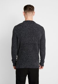 Tmavě šedý pletený svetr se strukturovaným vzorem, pružnými manžetami a lemem. Pohled z zadní strany, s kulatým výstřihem.