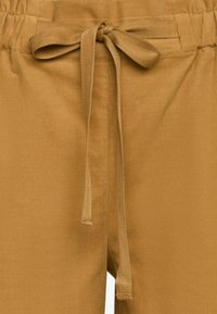 Pantaloni in cotone marrone con vita regolabile con cordino. Presentano una texture morbida e un dettaglio legato per una vestibilità regolabile. Ideali per un look casual.