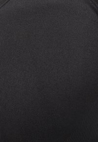 Svart stickad tyg med en mjuk textur och ribbat mönster, med en sömlös design som formar sig jämnt utan hårdvarudetaljer.