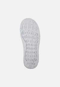 Sole di una scarpa, realizzata in gomma bianca con un motivo a macchie. Superficie testurizzata con punti di presa circolari e scanalature di flessibilità per una migliore trazione.
