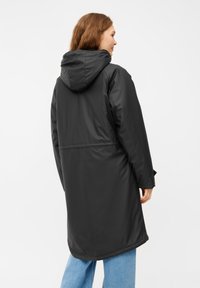 Parka nera impermeabile con cappuccio, caratterizzata da una vestibilità rilassata, design di lunghezza media e una texture liscia; completata da tasche laterali.