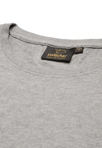 T-shirt in cotone grigio con scollo rotondo, maniche corte e un'etichetta con il logo "switcher" decorata in oro vicino al colletto.