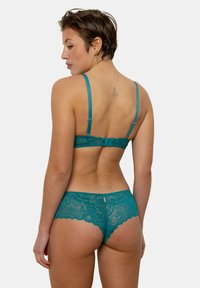Soutien-gorge en dentelle turquoise et culotte assortie avec des bords festonnés et un détail découpé à l'arrière. Bretelles ajustables pour un ajustement personnalisé.