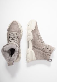 Harmaat mokkasaappaat, joissa on tekoturkislining, paksut kermaiset pohjat, tekstuuriset yksityiskohdat ja sivuvetoketju. Nyörit säädettävään istuvuuteen.