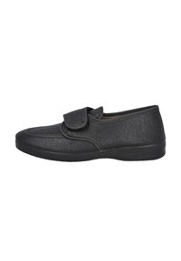 Zapato de tela negra con superficie texturizada, con una tira de Velcro, puntera redondeada y suela de goma flexible. Diseño plano adecuado para uso casual.