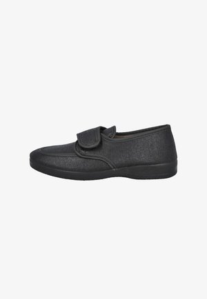 Zapato de tela negra con superficie texturizada, con una tira de Velcro, puntera redondeada y suela de goma flexible. Diseño plano adecuado para uso casual.