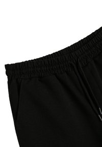Pantalon de survêtement noir avec une taille élastique, cordon de serrage et poches latérales, fabriqué à partir d'un tissu doux avec une couleur unie.