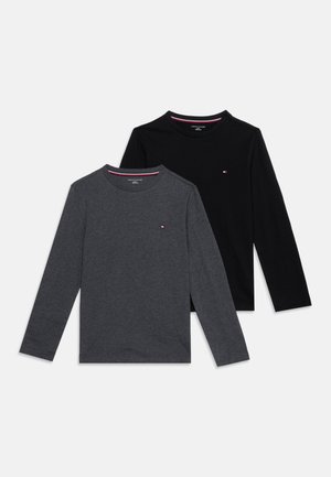 To langærmede crew neck-shirts, en mørkegrå og en sort, hver med et lille rødt, hvidt og blåt logo på brystet.