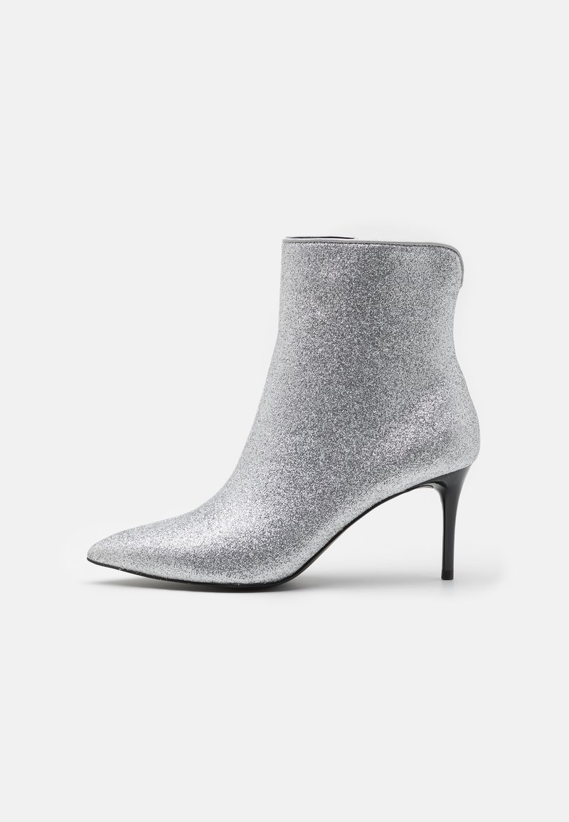 Botín de tobillo plateado con glitter, punta afilada y tacón de 4 pulgadas. Textura suave y diseño elegante, con una silueta ajustada.