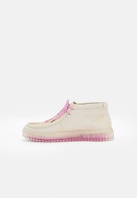 Bottes cheville beige clair avec des lacets roses, une tige texturée et une semelle dégradée transparente rose. Caractérisées par un bout rond.