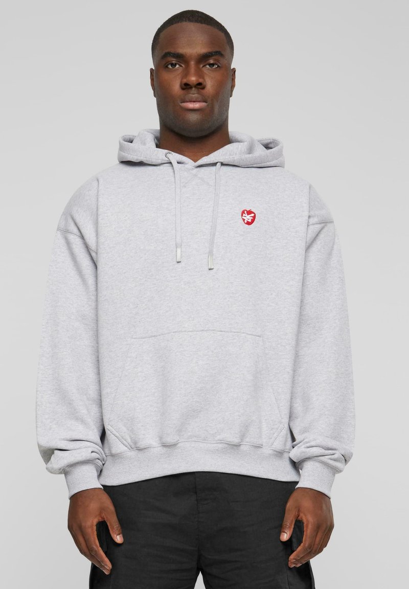 Grauer Kapuzenpullover mit einer Fronttasche, der ein kleines rotes Logo auf der Brust hat. Er hat eine lockere Passform und gerippte Bündchen.