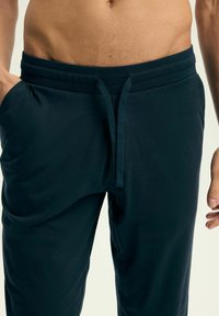 Granatowe spodnie dresowe wykonane z miękkiego materiału, z elastycznym pasem, ściągaczem i bocznymi kieszeniami dla wygody.