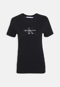 Camiseta de algodón negra con cuello redondo, mangas cortas y un logo gráfico plateado en la parte frontal con "CALVIN KLEIN JEANS" y "ck".