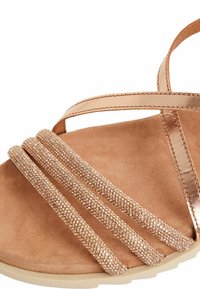 Sandal in oro rosa con tre cinturini di strass texturizzati su una morbida soletta in suede color tan e una suola leggera e flessibile.