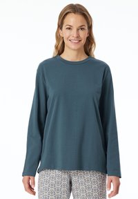 Dlouhý rukáv, top s kulatým výstřihem ze tmavě modré látky, s volným střihem. V kombinaci s vzorovanými kalhotami ve světlých barvách. Hladká textura.