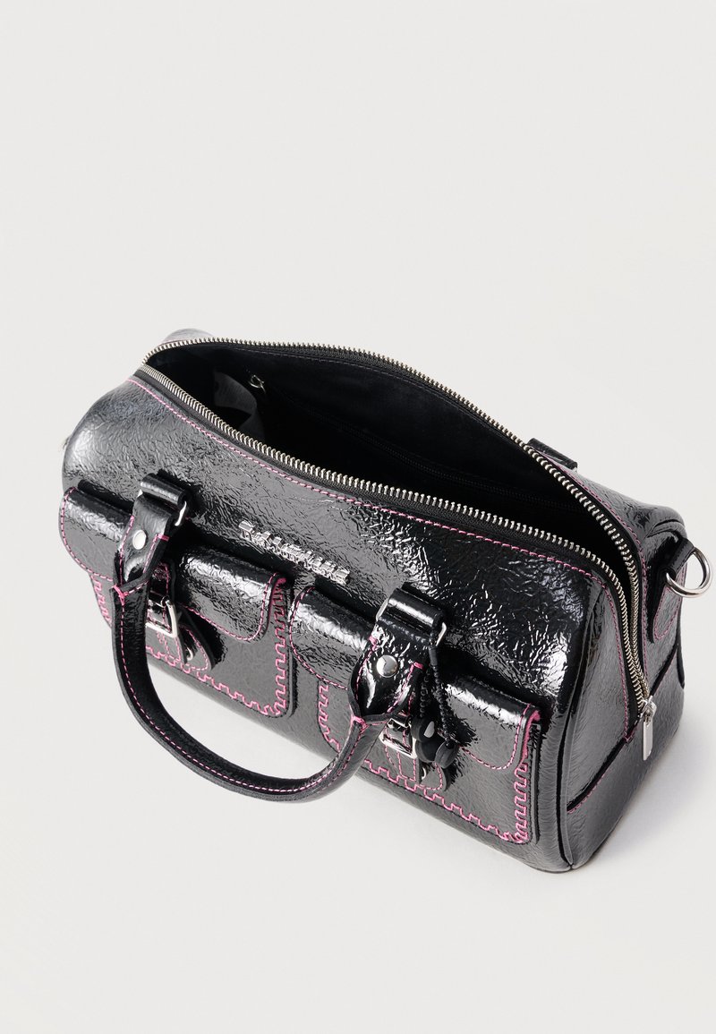 Zwarte handtas met textuur en roze stiksel, twee voorvakken met gespen, bovenhandgrepen en een gedeeltelijk open ritssluiting die de binnenkant toont.