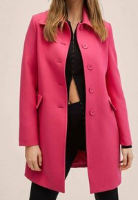 Abrigo rosa brillante hecho de un material estructurado, con un cuello, cinco botones y bolsillos laterales; diseño de longitud media con un corte ajustado.