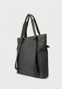 Μαύρη τσάντα tote με ρυθμιζόμενους ιμάντες, κατασκευασμένη από ανθεκτικό ύφασμα. Διαθέτει κομψό σχεδιασμό με πλαϊνές τσέπες και ελάχιστες μεταλλικές λεπτομέρειες.
