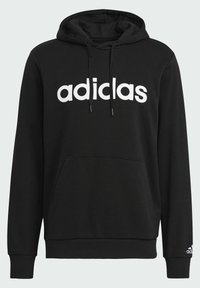Felpa nera con cappuccio e tasca a marsupio, logo "adidas" bianco. Presenta un cappuccio regolabile con lacci e polsini e orlo a coste. Tessuto morbido.