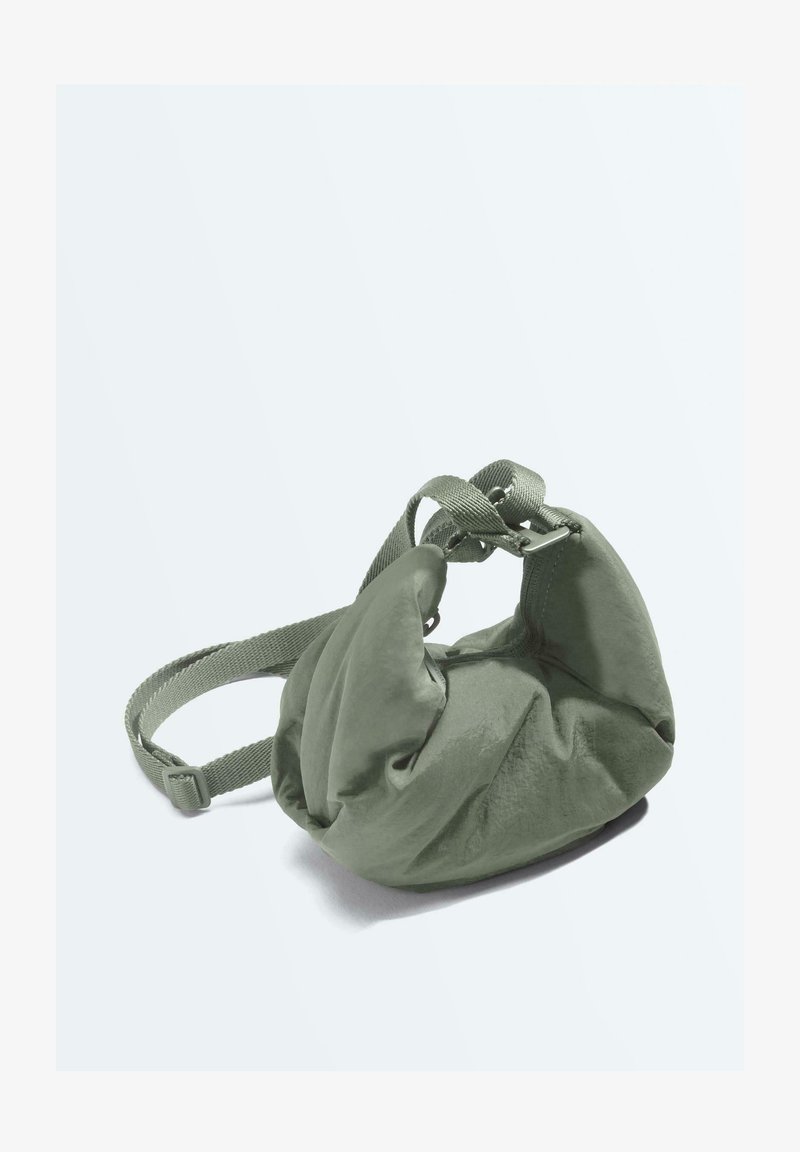 Mehka majhna torbica olivno zelene barve z nastavljivim tkanim trakom in z boranim, zaobljenim tekstilnim oblikovanjem na enostavni podlagi.