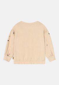 Beige mikina s nadýchanými rukávy a žebrovanými manžetami. Obsahuje barevnou výšivku motýlů podél rukávů a elastický lem.