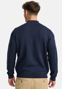 Marineblauer Strickpullover mit hohem Kragen, gerippten Bündchen und Saum. Glatte Textur mit passendem Design, von hinten betrachtet.