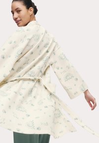 Accappatoio crema chiaro con tessuto texturizzato, caratterizzato da motivi in teal di sole, conchiglie e uccelli. Include una cintura e maniche larghe.