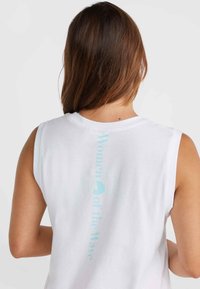 Vit ärmlös t-shirt med rund halsringning, som har ljusblå text "Women of the Wave" vertikalt längs ryggen. Mjuk tygtextur.