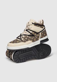 Zapatillas altas con un exterior de patrón beige y marrón, con cordones negros, una entresuela blanca y una suela texturizada negra.