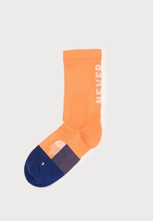 Orangene und marineblaue Socke mit dem Wort "NEVER" in Weiß an der Seite und dem The North Face Logo auf dem oberen Bereich des Fußes.