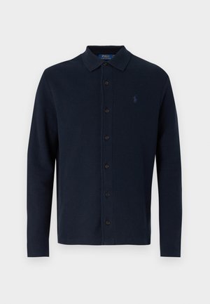 Tricou polo cu mâneci lungi de culoare bleumarin, cu guler, închidere cu nasturi și un logo mic pe piept, fabricat dintr-un material de bumbac texturat.