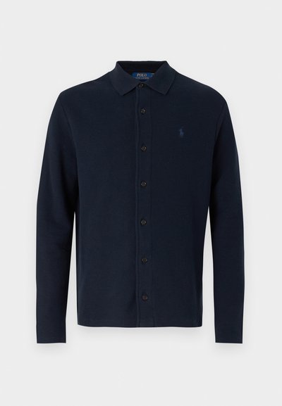 Tengerészkék hosszú ujjú poloing, galléros nyakkal, gombos elülső záródással és kis logóval a mellkasán, textúrált pamut anyagból készült.