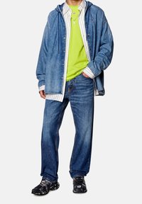 Denim jacket with hood, green T-shirt, striped shirt underneath, loose jeans, and black sneakers with a patterned sole.