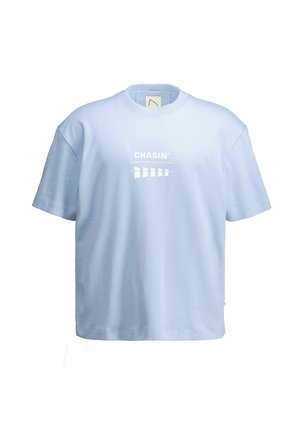 Svetlomodré tričko s krátkym rukávom s bielym nápisom „CHASIN’ Engineered Performance Jeanswear“ a geometrickým vzorom na prednej strane v strede.