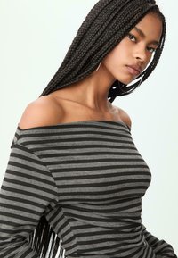 Schoudervrije gestreepte top in grijs en zwart, met een aansluitend ontwerp van zachte stof en lange mouwen. Accentuering met een geribbelde textuur.